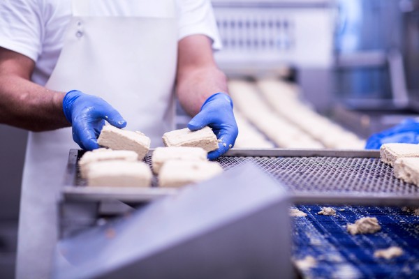 Trabajador de la industria alimenticia colocando bloques de producto sobre una rejilla metálica de secado.