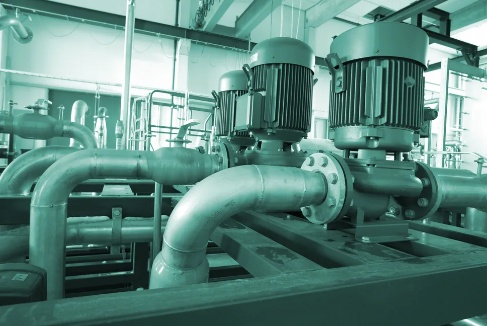 Maquinaria de ingeniería industrial con grandes motores eléctricos y tuberías verdes alineadas para procesos de producción.
