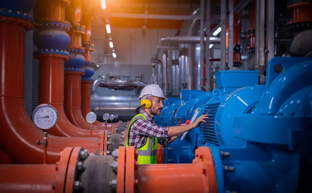 Especialista en ingeniería industrial realizando una inspección técnica de motores y manómetros en una planta moderna.
